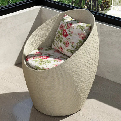 Fauteuil oeuf rotin beige lin sur un balcon