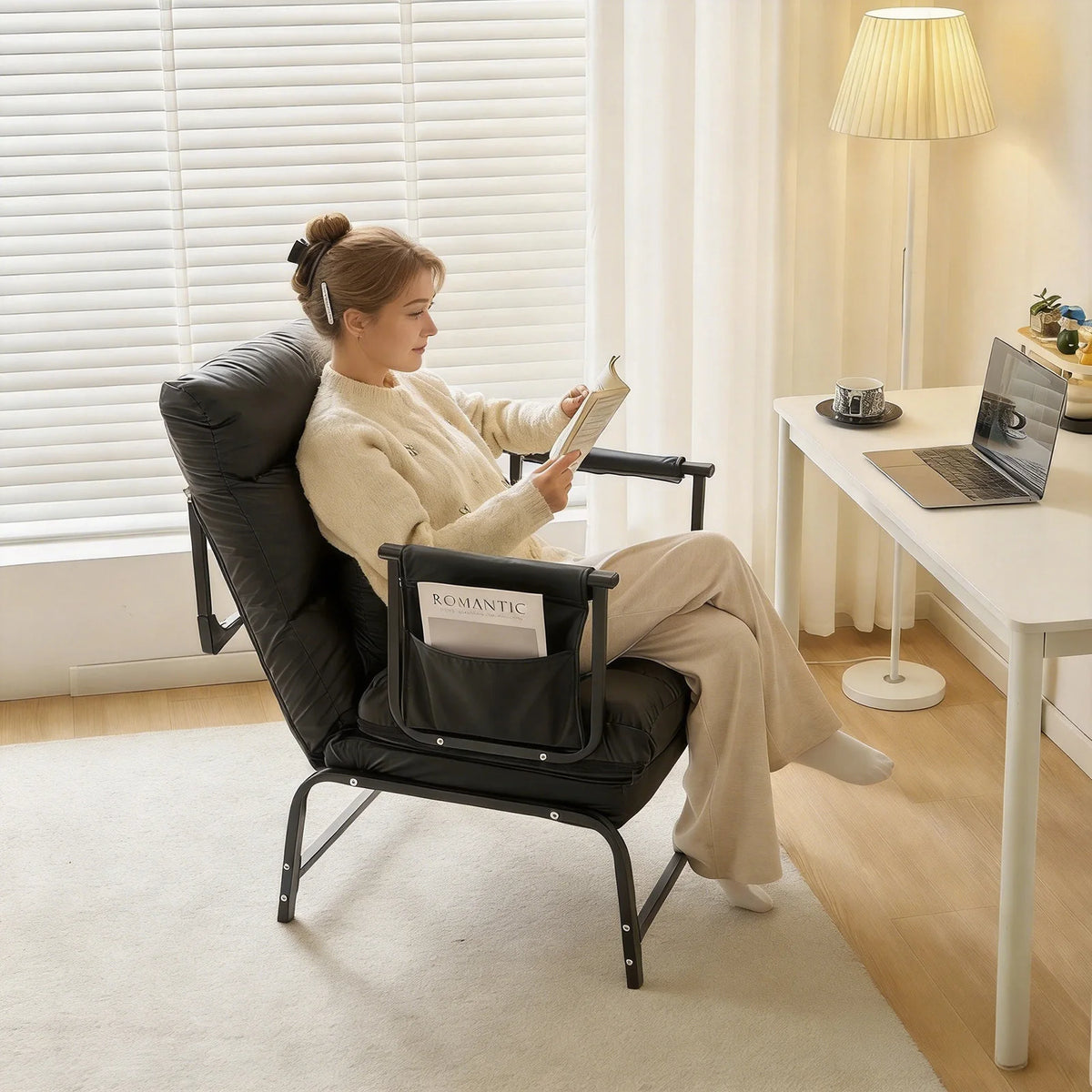 Femme lisant dans un fauteuil-lit convertible 1 place noir près d'un bureau