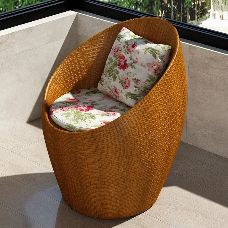Fauteuil oeuf rotin marron miel sur un balcon