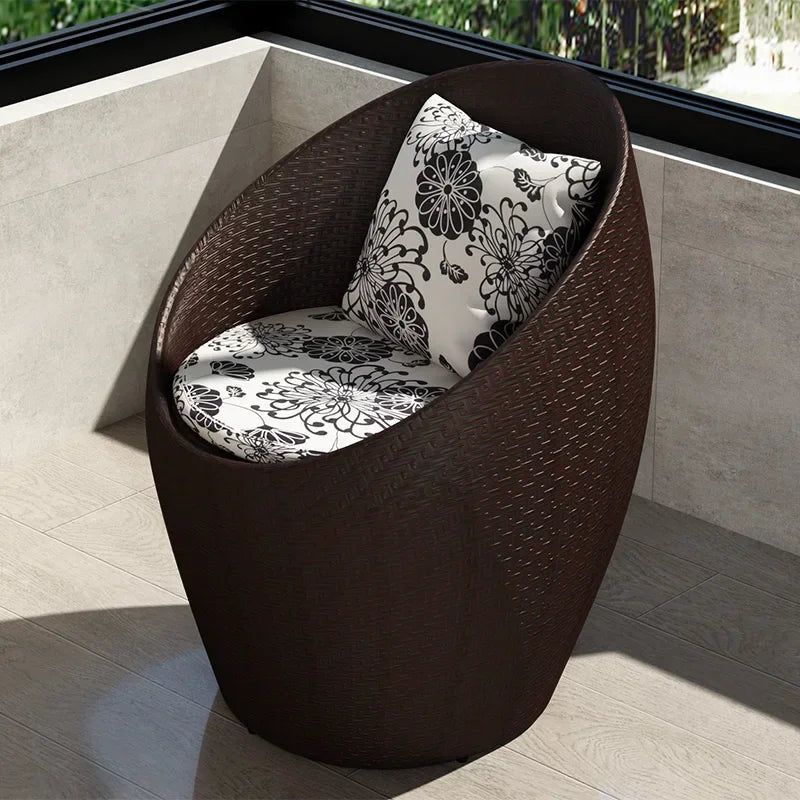 Fauteuil oeuf rotin marron chocolat sur un balcon