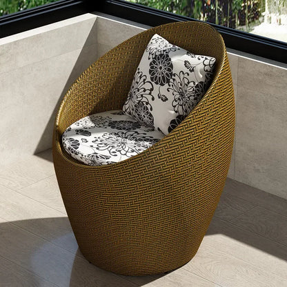 Fauteuil oeuf rotin marron doré sur un balcon